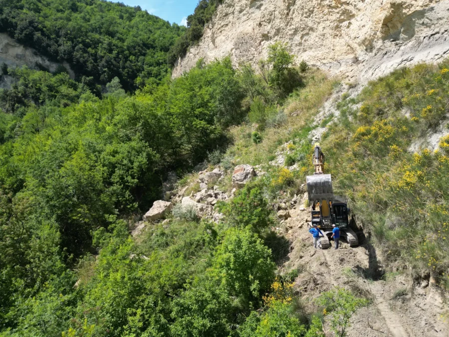 Escavatore che rimuove blocchi instabili dalla scarpata durante il disgaggio