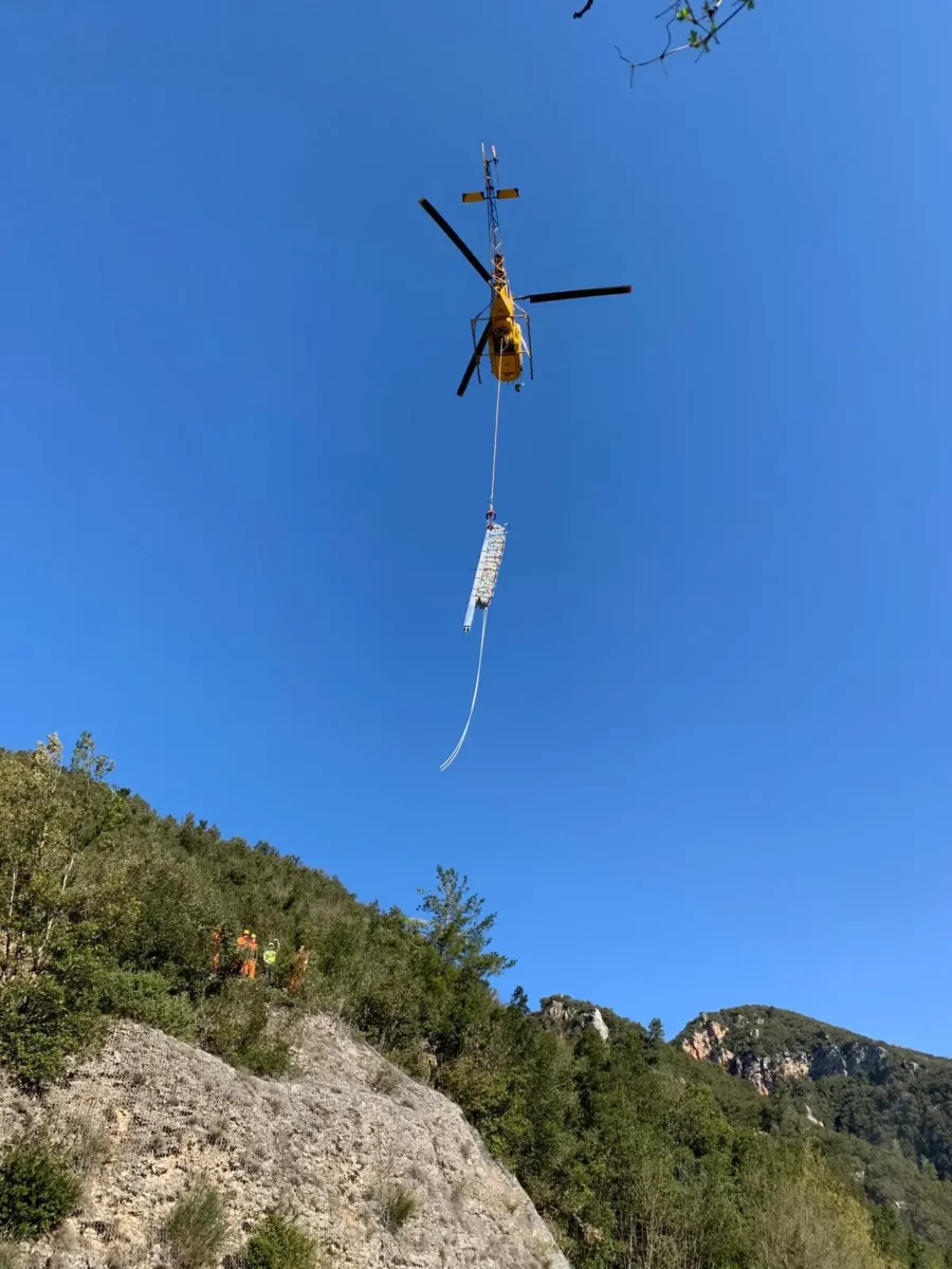 Elicottero in volo con un carico di materiali sopra il versante