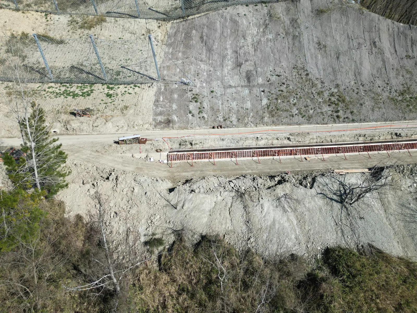 Scarpata protetta da rete con canaletta in calcestruzzo lungo la strada