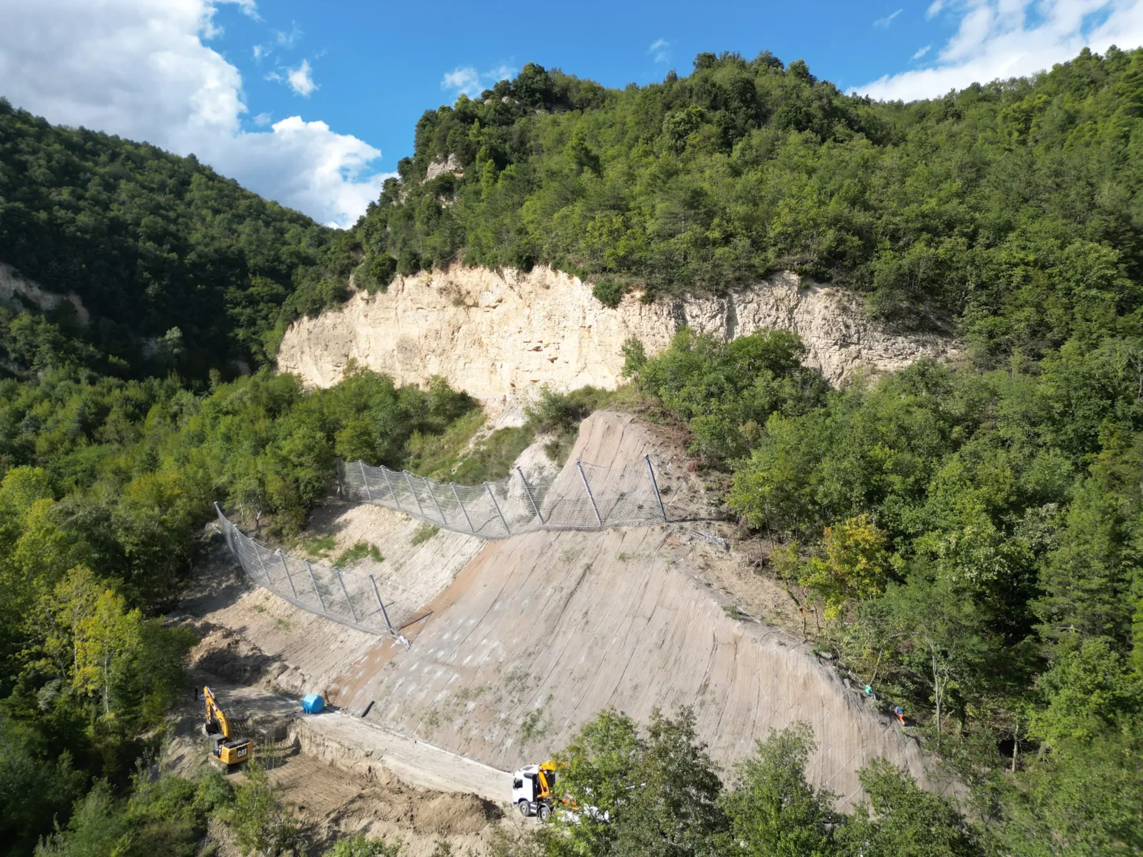 Versante appenninico messo in sicurezza: barriere paramassi e rete in aderenza sotto una parete rocciosa